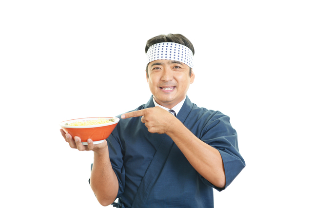 ラーメンを手に持ち指差す店員